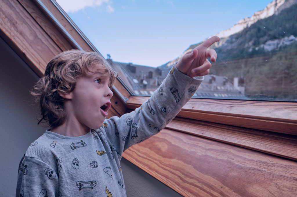 Shocked boy observing mountains through window in house